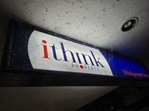 An illuminated sign covered in cobwebs and dirt