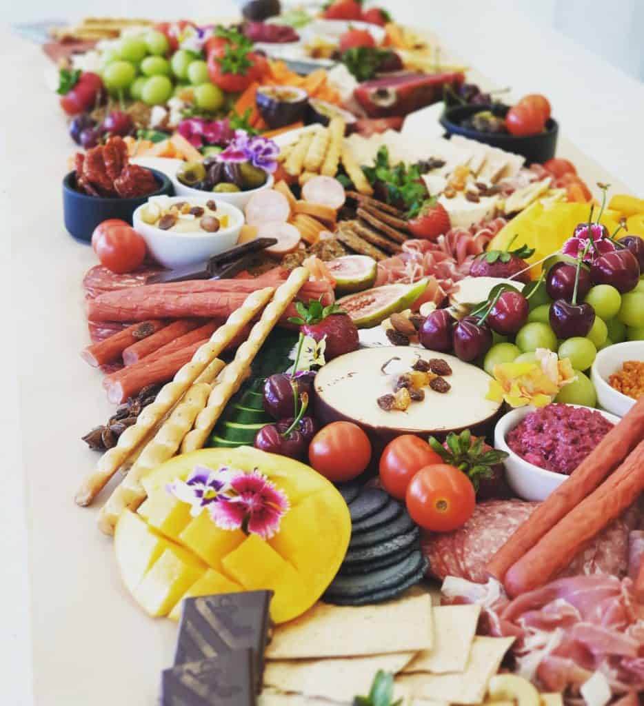 A table laid with fruits, vegetables, crackers, cold meats, chocolate and more.