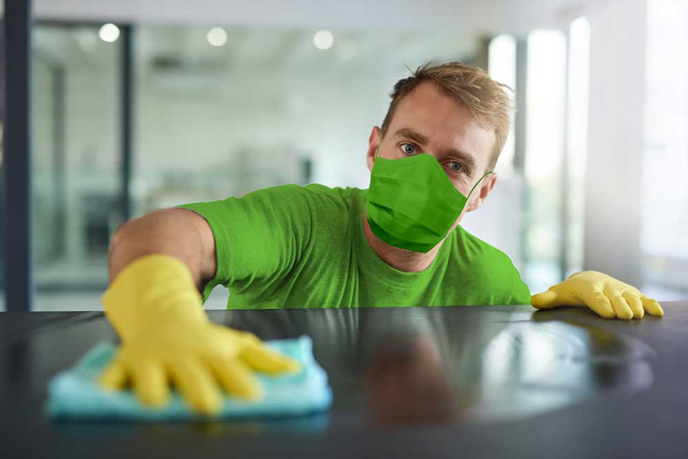 man wearing a mask and gloves doing office cleaning