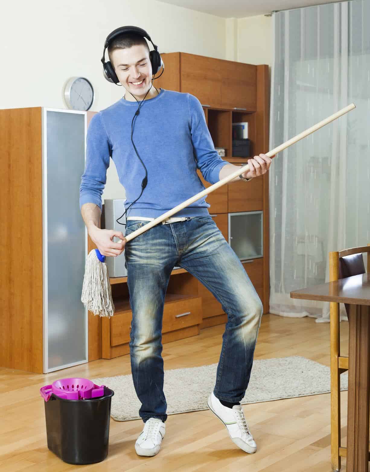 man wearing headset and dancing to the beat while holding a mop