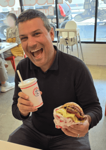 a happy man enjoying a burger and a shake